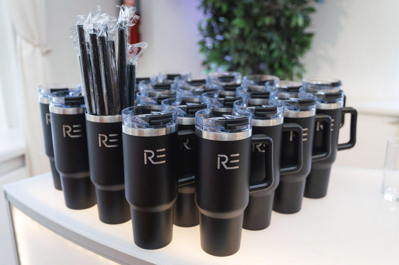 Rows of branded black event tumblers and pencils